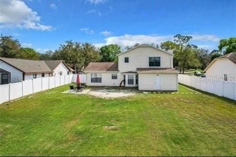 back of property with a fenced backyard, a yard, and a patio area