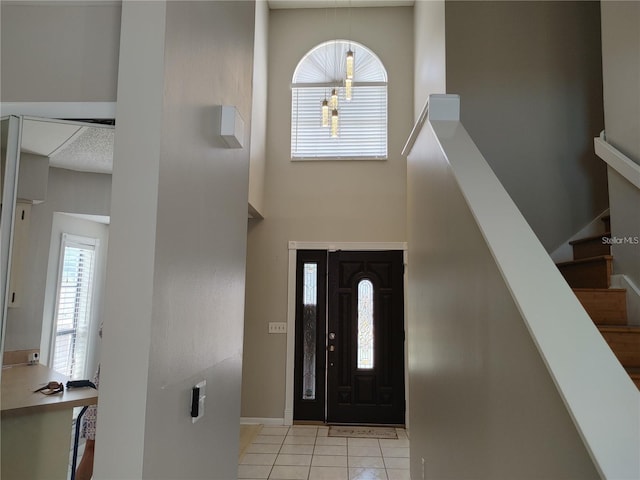 foyer with baseboards, a high ceiling, light tile patterned floors, and stairway