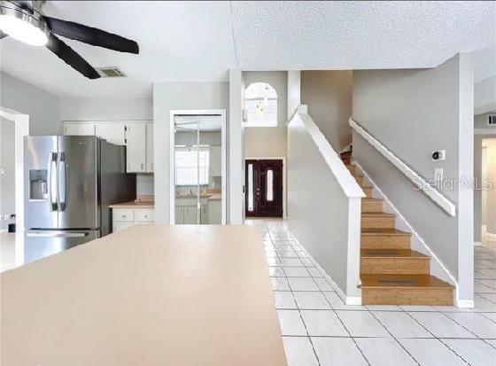 kitchen featuring white cabinets, ceiling fan, stainless steel fridge, light tile patterned floors, and visible vents