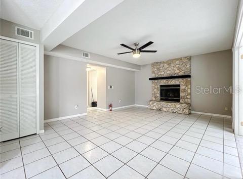 unfurnished living room featuring visible vents, ceiling fan, and light tile patterned floors