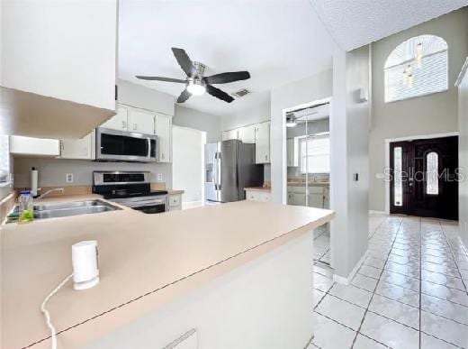 kitchen with white cabinets, ceiling fan, light countertops, stainless steel appliances, and light tile patterned floors
