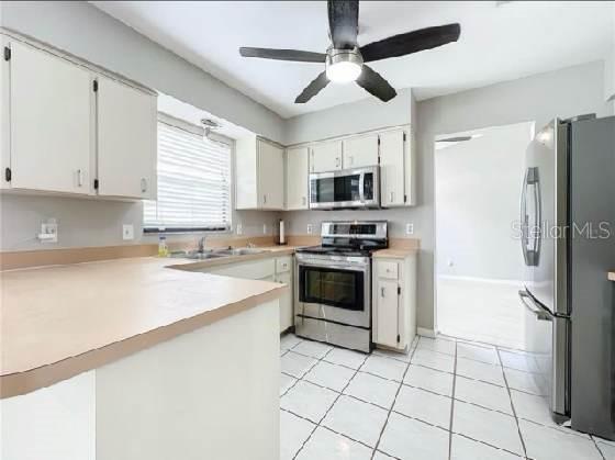 kitchen featuring ceiling fan, light countertops, white cabinets, a peninsula, and stainless steel appliances