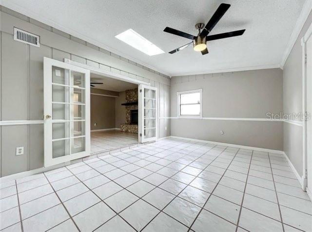 unfurnished room featuring tile patterned floors, ceiling fan, and a textured ceiling