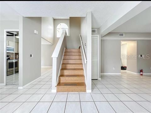 stairway featuring tile patterned floors, baseboards, a textured ceiling, and visible vents