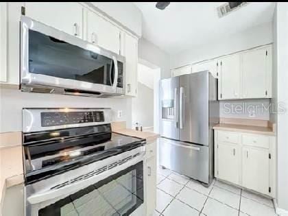 kitchen with light countertops, light tile patterned floors, white cabinets, and stainless steel appliances