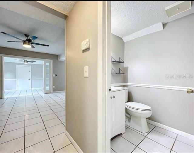 bathroom featuring a textured ceiling, tile patterned floors, baseboards, vanity, and toilet