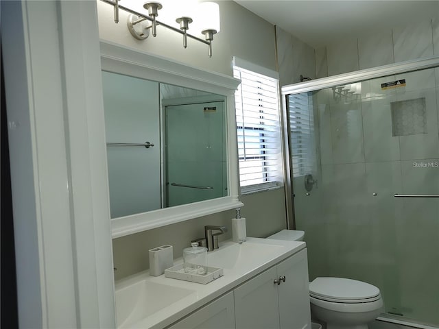 bathroom with toilet, a notable chandelier, a shower stall, and vanity