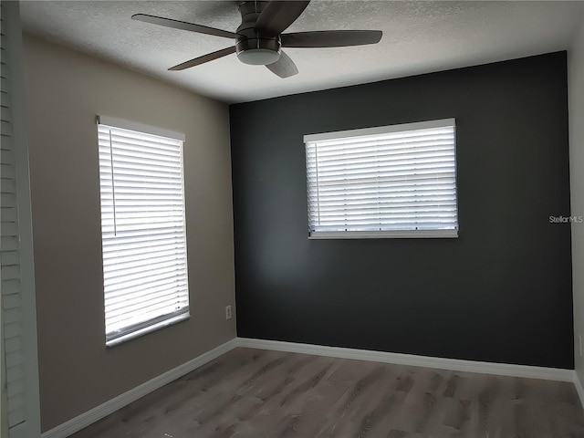 spare room with a ceiling fan, a textured ceiling, wood finished floors, and a wealth of natural light