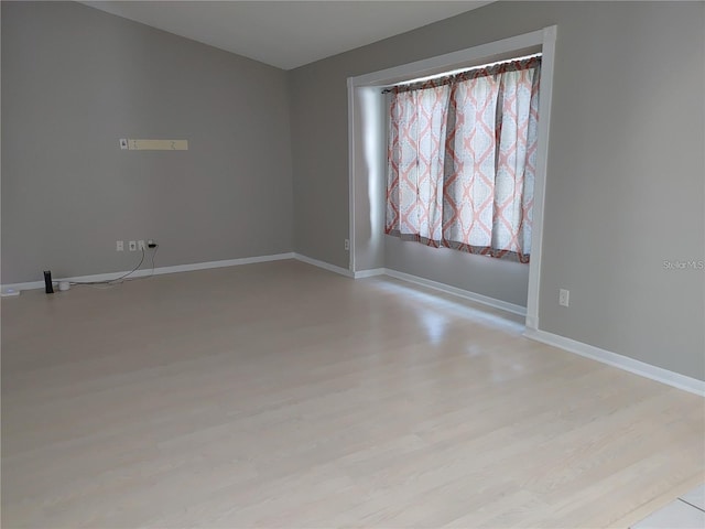 unfurnished room with baseboards and light wood finished floors