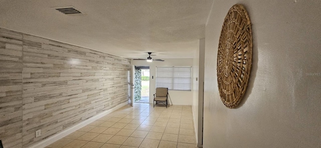 hall with light tile patterned floors, baseboards, a textured ceiling, and visible vents