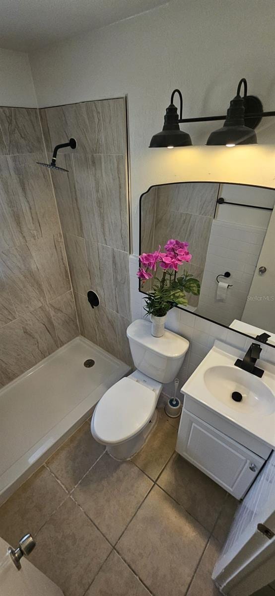 full bathroom with toilet, tiled shower, tile patterned flooring, and vanity