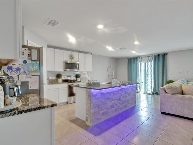 kitchen featuring dark stone countertops, visible vents, open floor plan, white cabinets, and appliances with stainless steel finishes
