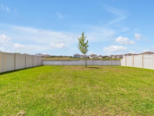 view of yard with a fenced backyard, a water view, and a residential view