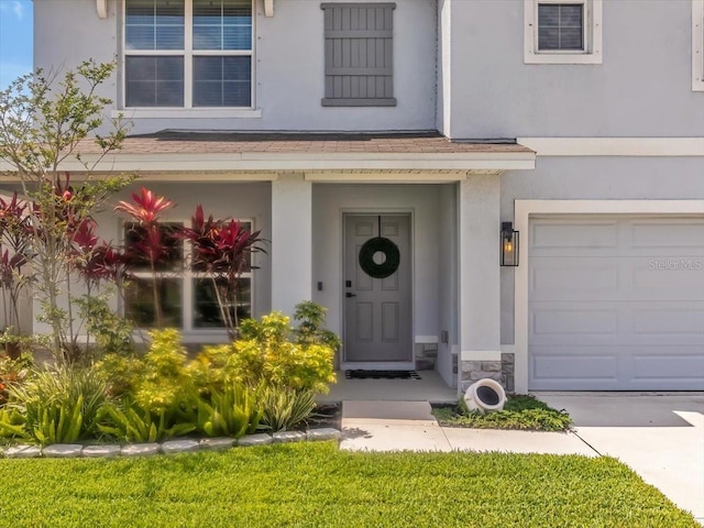 property entrance featuring an attached garage, stucco siding, and stone siding