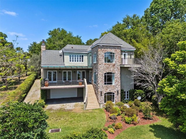 rear view of house with a chimney, stairway, french doors, and stone siding