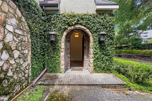 view of exterior entry featuring stone siding and stucco siding