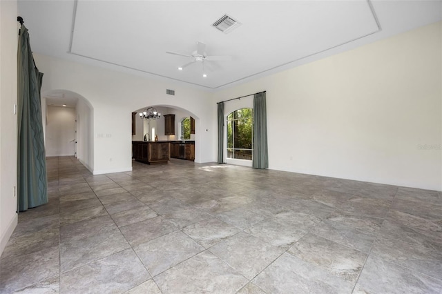 unfurnished living room with arched walkways, baseboards, ceiling fan with notable chandelier, and visible vents