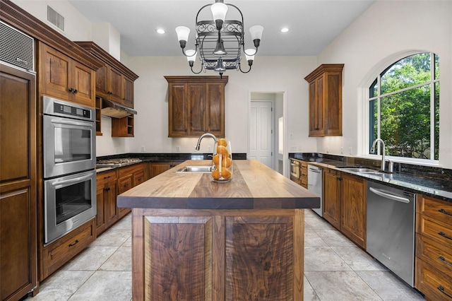 kitchen featuring appliances with stainless steel finishes, butcher block counters, a sink, and visible vents