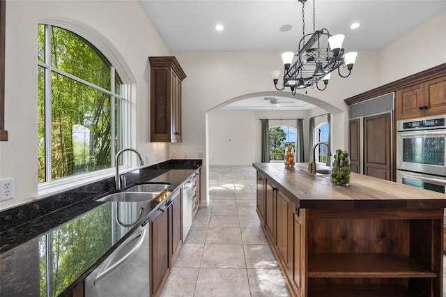 kitchen featuring open shelves, a sink, arched walkways, butcher block countertops, and stainless steel appliances