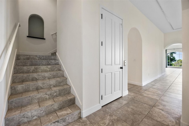 staircase featuring arched walkways and baseboards