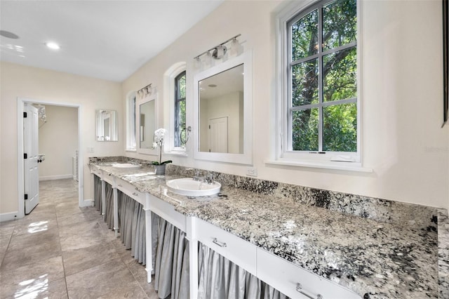 bathroom with a sink, baseboards, recessed lighting, and double vanity