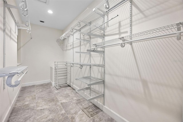 walk in closet featuring visible vents and stone finish floor