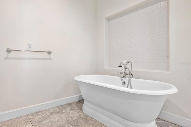 full bath with baseboards, a freestanding bath, and tile patterned floors