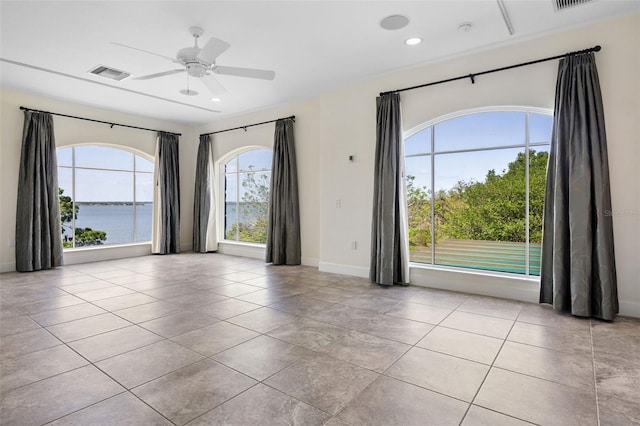 unfurnished room featuring baseboards, ceiling fan, visible vents, and tile patterned floors
