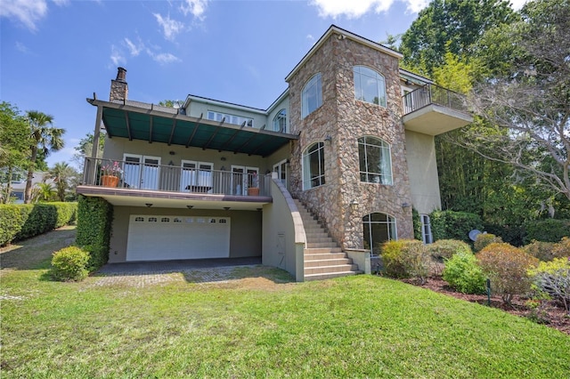 view of front of house with a front lawn, a balcony, stucco siding, a chimney, and an attached garage