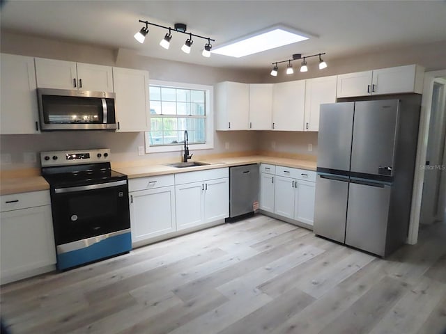 kitchen with a sink, rail lighting, stainless steel appliances, and light countertops