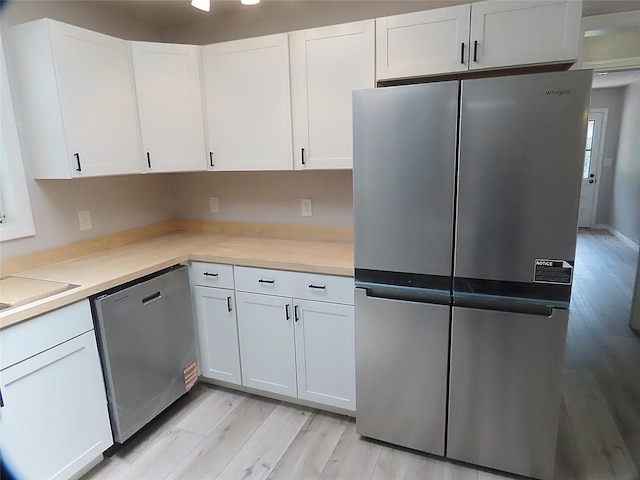 kitchen with white cabinets, light countertops, appliances with stainless steel finishes, and light wood-style floors