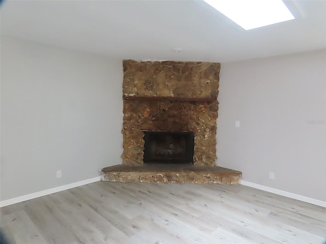 unfurnished living room with baseboards, a fireplace, and wood finished floors