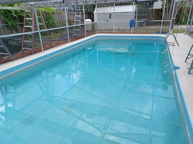 view of swimming pool with glass enclosure, a fenced in pool, and a fenced backyard