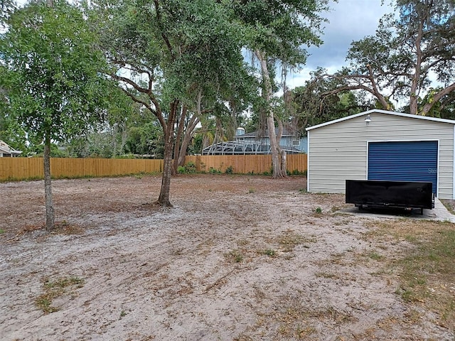 view of yard with fence, a detached garage, and an outdoor structure