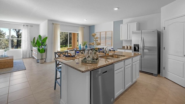 kitchen featuring a sink, appliances with stainless steel finishes, light stone countertops, and a healthy amount of sunlight