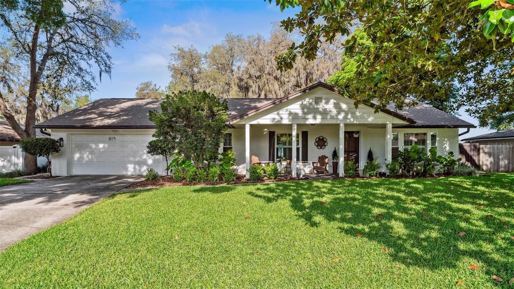 819 E Harbour Ct, Ocoee, FL 34761 - ranch-style home featuring fence, covered porch, a garage, concrete driveway, and a front lawn
