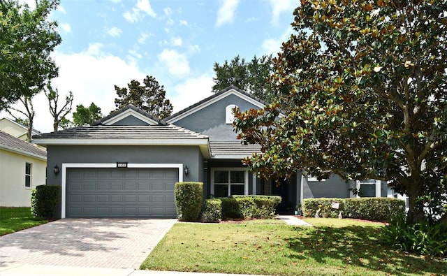 view of front facade with a garage, decorative driveway, stucco siding, and a front lawn