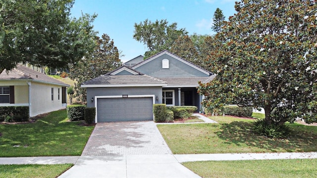 view of front of property featuring decorative driveway, a garage, stucco siding, and a front lawn
