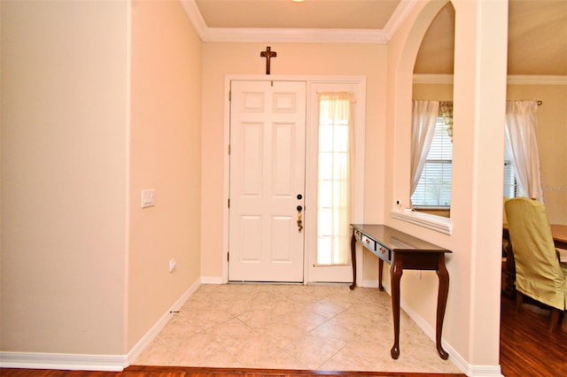 foyer entrance with crown molding, arched walkways, baseboards, and tile patterned floors