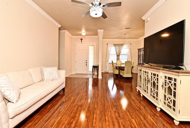 living area featuring ornamental molding, dark wood-type flooring, ceiling fan, and baseboards