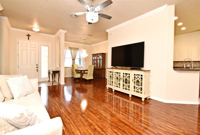 living area featuring a ceiling fan, wood finished floors, ornamental molding, baseboards, and recessed lighting
