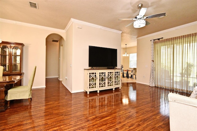 living room featuring wood finished floors, arched walkways, a ceiling fan, crown molding, and baseboards