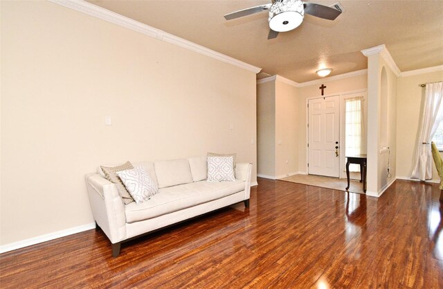 living room featuring wood finished floors, crown molding, ceiling fan, and baseboards