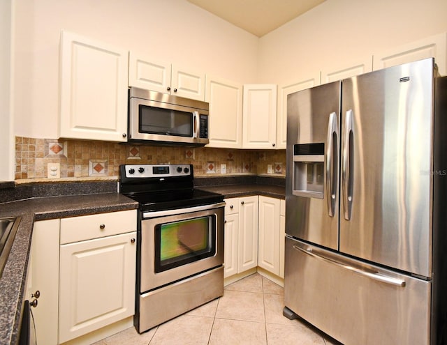 kitchen featuring stainless steel appliances, white cabinetry, dark countertops, and tasteful backsplash