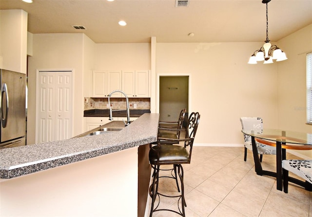 kitchen featuring freestanding refrigerator, a chandelier, recessed lighting, a sink, and a kitchen breakfast bar