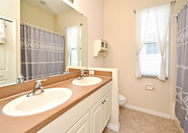 full bathroom with toilet, double vanity, baseboards, and tile patterned flooring