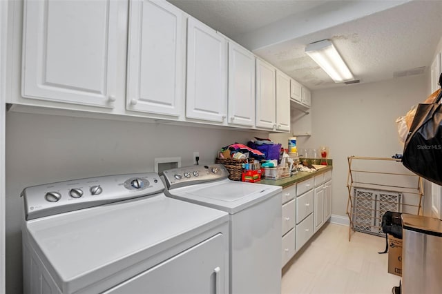 5108 Sailwind Cir, Orlando, FL 32810 - laundry area with washing machine and dryer, cabinet space, a textured ceiling, and light floors