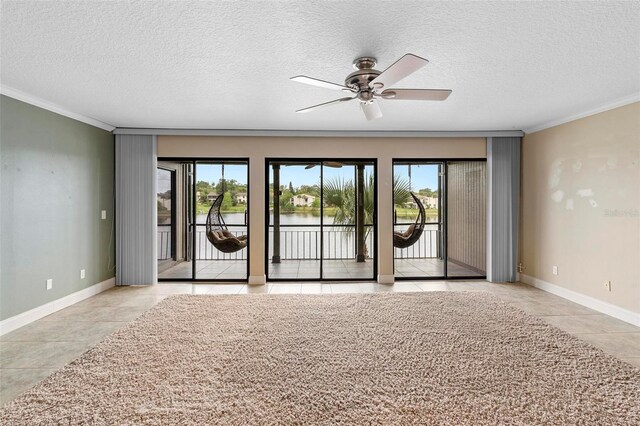 tiled empty room featuring a ceiling fan, a healthy amount of sunlight, and crown molding