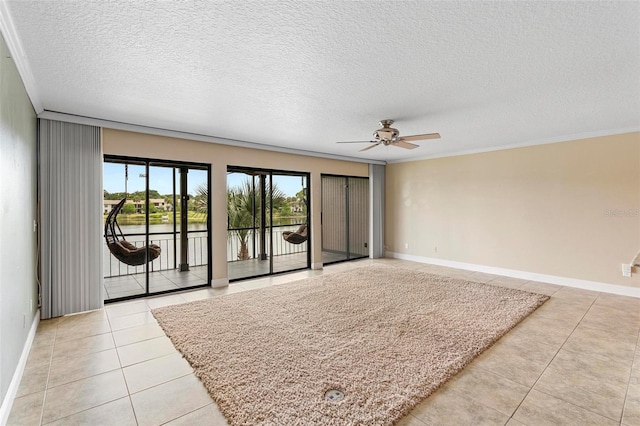 empty room with light tile patterned flooring, a textured ceiling, crown molding, a ceiling fan, and baseboards