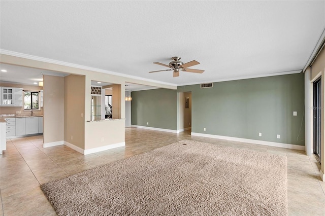 unfurnished living room with ornamental molding, visible vents, a ceiling fan, light tile patterned floors, and baseboards